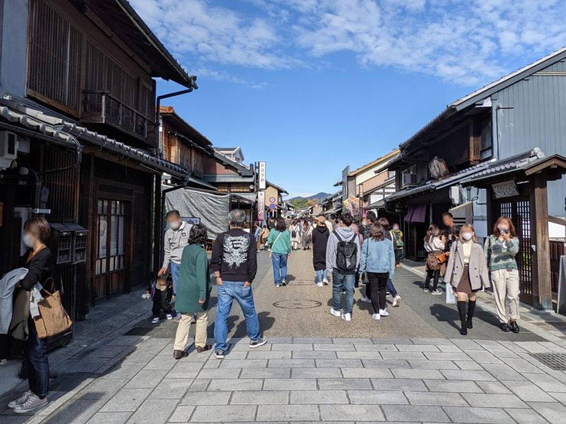 歴史的な木造建築が並ぶ犬山城下町のメインストリートを歩く多くの観光客。晴天の昼間の風景。