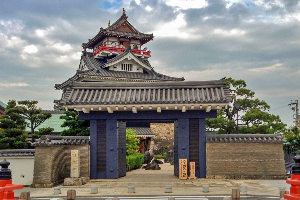 清洲城の重厚な瓦屋根の門を正面から捉えた写真。門の奥には再建された天主閣がそびえ立っている。