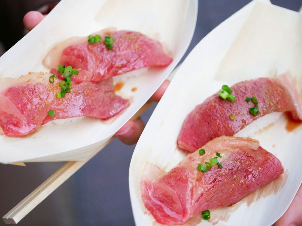 木の舟皿に盛り付けられた、サシの入った美味しそうな飛騨牛の握り寿司。