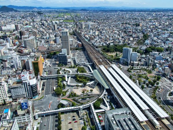 岐阜シティ・タワー43の展望室から東方向を見下ろした風景。地上152メートルの高さから、JR岐阜駅の長いホームや線路、並走する道路、密集するビル群が一望でき、遠景には各務原市の山並みが連なっている。