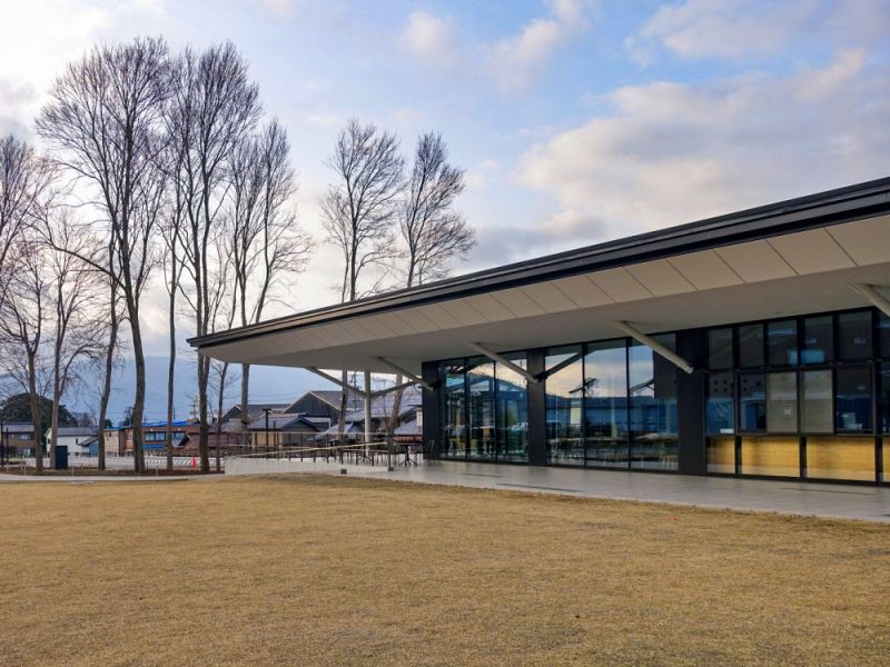 岐阜関ケ原古戦場記念館に隣接するレストラン「伊吹庵」の外観。大きなガラス張りのモダンな平屋建てで、手前には広々とした芝生広場と冬の木立が広がっている様子。