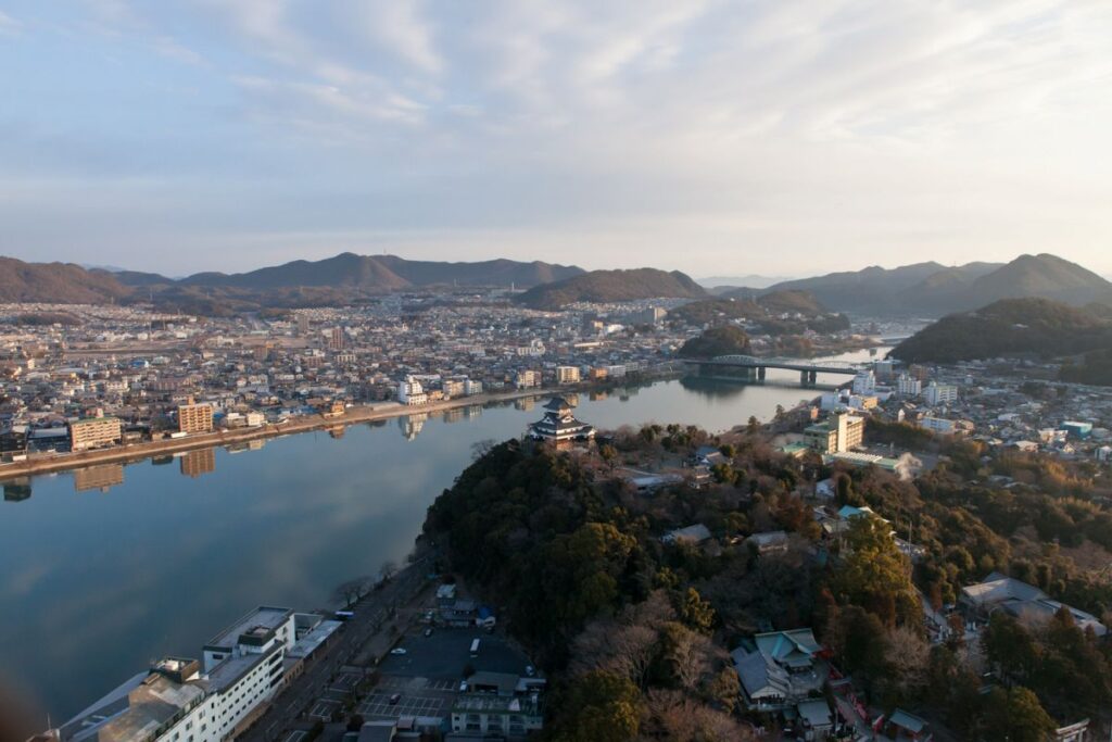 木曽川沿いの山頂に建つ犬山城の遠景と周囲の街並み。