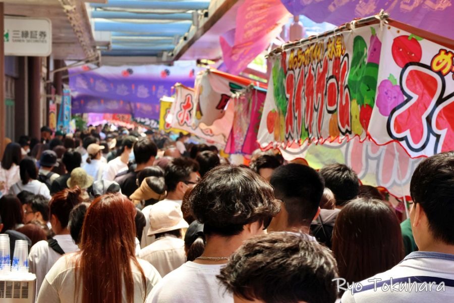 大垣まつりの開催中、多くの人々で埋め尽くされたアーケード下の通り。手前には「スカイロール」などの文字が書かれたカラフルな屋台の看板が並び、活気に満ちた祭りの様子を捉えたスナップ写真。