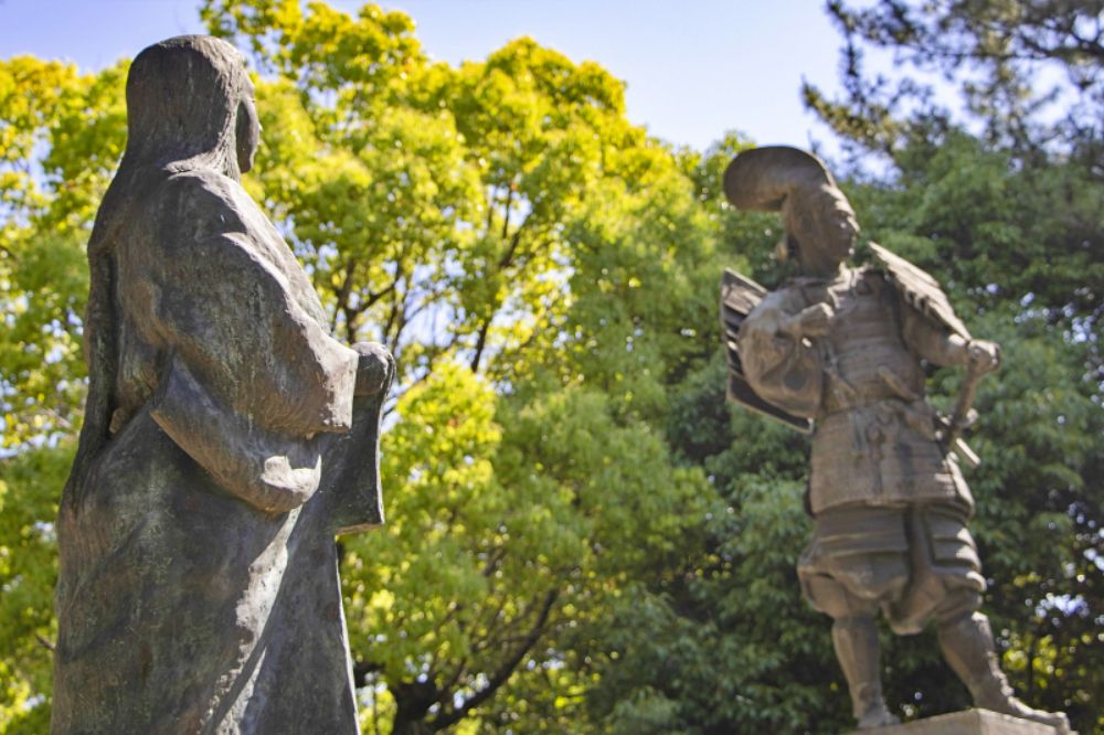 清洲古城跡公園にある、織田信長と正室・濃姫の銅像。手前に濃姫の背中越し、奥に信長の姿が映り、二人が向かい合っている様子。