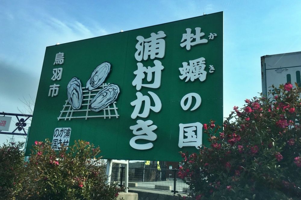 「牡蠣の国 浦村かき 鳥羽市」と書かれた大きな緑色の看板。