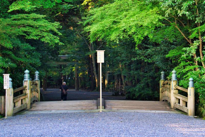 伊勢神宮・外宮の入り口にある、木造の緩やかな太鼓橋。背景には深い緑の森が広がっています。