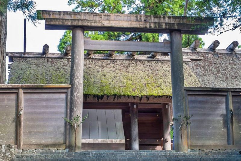 伊勢神宮・内宮の正宮前にある大きな木造の鳥居と、その奥に見える茅葺き屋根の社殿。手前には石段があります。